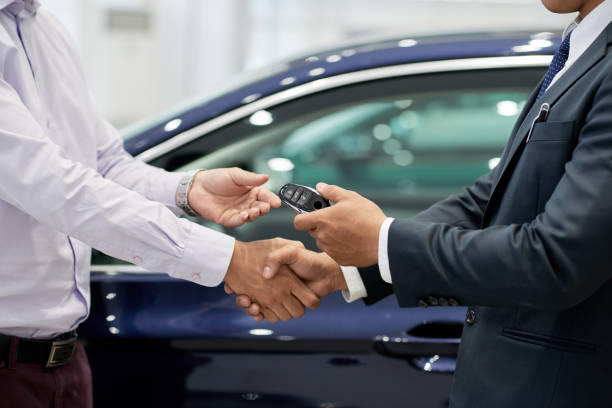 Salesman giving car keys to customer and shaking his hand